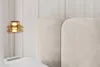 A close-up view of a beige upholstered headboard and a pendant light. Produktbild-Vorschau
