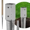 Close-up of metal fence post anchors partially inserted into the ground, with grass in the background. Voir les images du produit