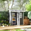 A dark gray plastic shed with white trim is shown in a backyard setting, with plants, firewood, and a grill nearby. Produktbild-Vorschau