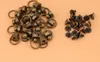 A pile of metal rivets with rings and a separate pile of screws on a light peach background. Náhled obrázku produktu