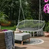 A hanging chair and ottoman set on a wooden deck in a garden setting. Náhľad obrázku produktu