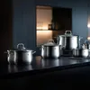 A set of stainless steel pots and pans arranged on a dark countertop. Náhľad obrázku produktu