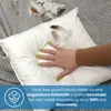 A hand pressing down on a white pillow, with feathers scattered on top. Produktbild-Vorschau