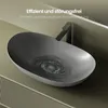 A modern matte gray oval washbasin with water swirling down the drain, set on a textured vanity. Produktbild-Vorschau