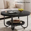 A round, black coffee table with two tiers, placed in a living room setting next to a sofa. Produktbild-Vorschau
