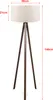 A floor lamp with a cream lampshade and a wooden tripod base, with dimensions indicated by text overlays. Produktbild-Vorschau