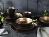 A table setting with black and gold stoneware plates, bowls, and mugs. Náhľad obrázku produktu
