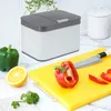 A kitchen counter with a compost bin, vegetables, and a cutting board. Produktbild-Vorschau