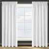 Two white curtains are hung on a curtain rod in front of a window with a grid pattern. The curtains are gathered at the top and hang down to the floor. The window shows a cloudy sky. Produktbild-Vorschau