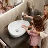 A woman and a child are washing their hands at a modern sink in a bathroom. Anteprima dell’immagine prodotto