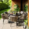 An outdoor dining set on a patio with a garden and wooden building in the background. Produktbild-Vorschau