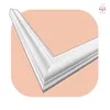 A close-up of a white corner molding piece, set against a light peach and white background. Anteprima dell’immagine prodotto