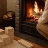 A person is adding wood to a fireplace, with fire burning inside. There are also some wooden blocks in the foreground. Produktbild-Vorschau