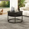A round coffee table with a marble-like top and a storage compartment sits on a gray rug in a living room. A sofa and a plant are visible in the background, and a large window shows a sunny outdoor scene. Anteprima dell’immagine prodotto