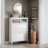 A white shoe cabinet with two flip drawers stands in a hallway, next to a wicker umbrella stand and a framed print on the wall. Anteprima dell’immagine prodotto