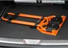 A folded orange and black sack truck is lying on the floor of a car trunk. Náhled obrázku produktu