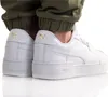 A close-up shot of the back and side of a pair of white Puma sneakers worn by a person. Produktbild-Vorschau