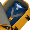 Close-up view inside an open yellow backpack, showing a folded blue shirt secured by a gray strap with an orange buckle. Produktbild-Vorschau