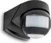 A black motion detector with a white sensor lens is mounted on a wall. Náhľad obrázku produktu