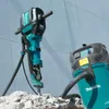 A heavy-duty demolition hammer and a vacuum cleaner are shown in an outdoor setting, with the hammer positioned over debris. Anteprima dell’immagine prodotto