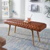 A brown quilted leather bench with wooden legs sits on a patterned rug in a well-lit room. Produktbild-Vorschau