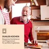 Two men in a kitchen, one older and laughing, the other younger and partially visible. An air fryer is visible in the background. A peach-colored overlay with text and an icon is in the foreground. Produktbild-Vorschau
