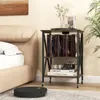 A bedside table with books and decor next to a bed, with a robot vacuum cleaner on the floor. Produktbild-Vorschau
