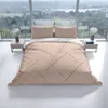 A bed with beige bedding featuring a striped pattern, set against a large window with a scenic view. Produktbild-Vorschau