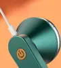 Close-up of a green fabric shaver with a white charging cable plugged in and a gold power button. Náhled obrázku produktu