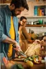 A family is preparing food in a kitchen. The father is cutting vegetables, while his daughters are watching and eating. Podgląd zdjęcia produktu