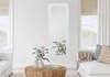 A modern living room with a mirror on the wall, a coffee table with vases and plants, and a sofa. Náhľad obrázku produktu