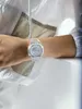 A person wearing a clear G-Shock watch on their wrist, with a white jacket. Voir les images du produit