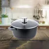 A black pot with a glass lid sits on a wooden table in a kitchen setting. Produktbild-Vorschau
