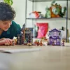 A young boy is playing with LEGO Harry Potter sets on a wooden table. The sets appear to be shops from Diagon Alley. Produktbild-Vorschau