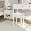 A white vanity stool is placed in front of a white vanity table, with a white nightstand to the left. The scene is set in a bedroom or dressing area. Anteprima dell’immagine prodotto