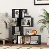 A black S-shaped bookshelf filled with various decorative items and books, placed next to a sofa in a living room. Podgląd zdjęcia produktu