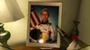 A framed portrait of an astronaut in a white and yellow spacesuit, with an American flag in the background. The portrait is on a table with a lamp and a vase. Produktbild-Vorschau