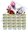 A set of glass jars with golden lids, accompanied by strawberries, flowers, and a packet of gelling sugar. Produktbild-Vorschau