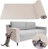 A product image showing a roll of beige carpet material, a grey sofa with a beige protector on one arm, and a cat scratching the protector. There is also an inset image of hands cutting the material with scissors. Produktbild-Vorschau
