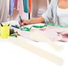 A person is working at a desk with sewing supplies, including fabric and a measuring tape. Two bone folders are in the foreground. Produktbild-Vorschau