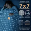 A woman sleeping comfortably under a weighted blanket with a grid pattern overlay indicating a chamber system. Produktbild-Vorschau
