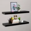 Two black floating shelves mounted on a textured wall, one above the other, with decorative items on them. Náhľad obrázku produktu