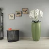A living room corner with decorative wall art, a side table with a cup, and a large artificial orchid in a green pot. Voir les images du produit