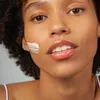 Close-up of a woman's face with a stripe of cream on her cheek. Produktbild-Vorschau