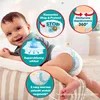 A baby lying on a pillow, with callouts highlighting features of a diaper. Podgląd zdjęcia produktu