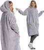 A woman wearing a grey hoodie blanket, shown from the front and side. Produktbild-Vorschau