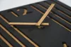 A close-up view of a modern black and oak wall clock. Anteprima dell’immagine prodotto