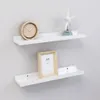 Two white floating shelves mounted on a light gray wall, decorated with a clock and a starfish on the top shelf, and a picture frame on the bottom shelf. Anteprima dell’immagine prodotto
