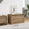 A wooden shoe bench with a framed picture and decorative items on top, placed in a living room setting. Produktbild-Vorschau