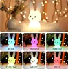 A collage of images showing a white bunny-shaped night light in different colors, with text labels below each color. Produktbild-Vorschau